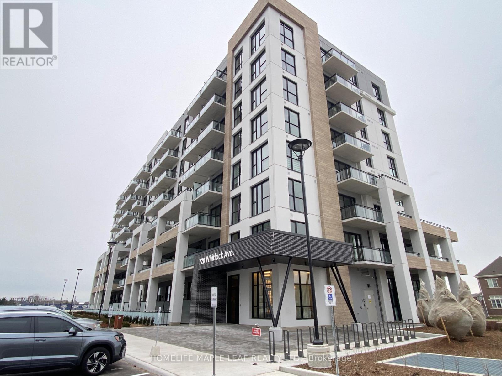 A modern apartment building with a car parked in front.