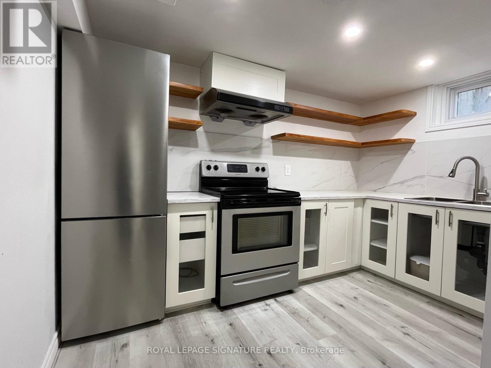 A modern kitchen with a stainless steel refrigerator, oven, and cabinets.
