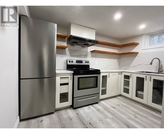 A modern kitchen with a stainless steel refrigerator, oven, and cabinets.