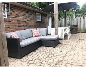 A black wicker couch with red and white pillows sits on a patio.