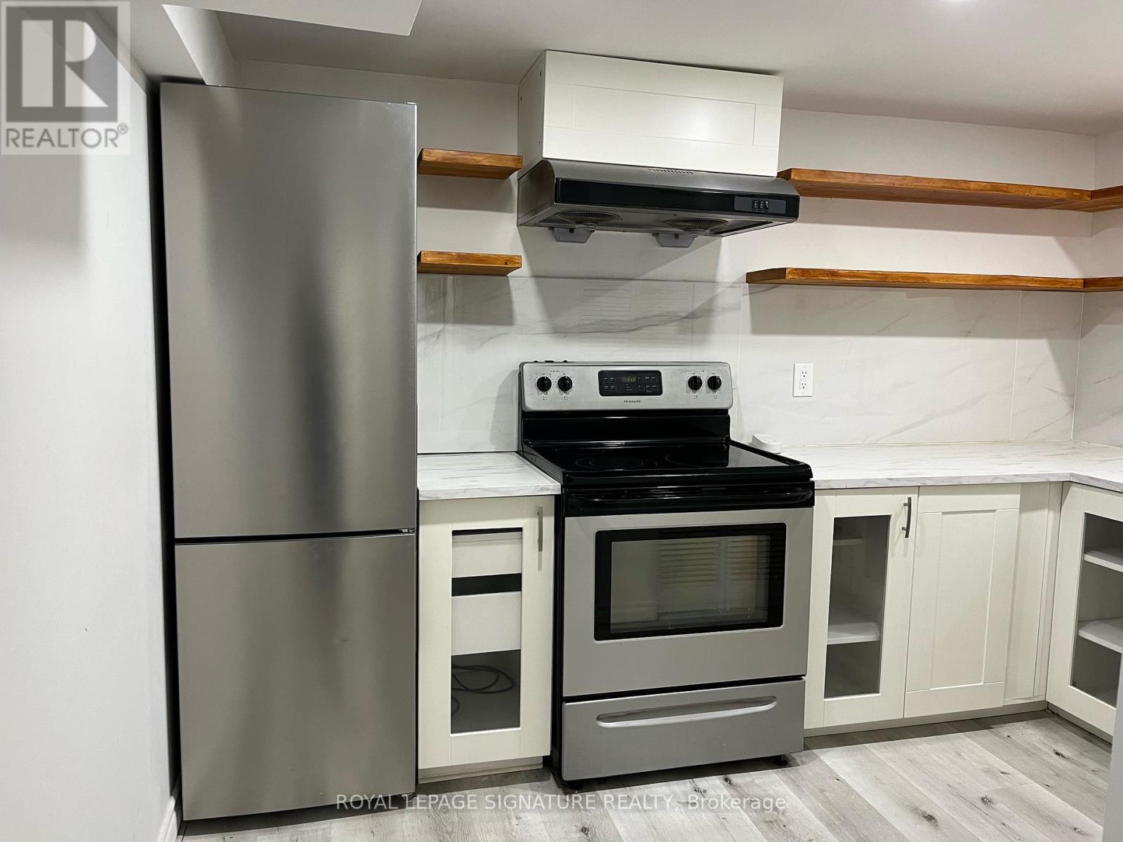 A modern kitchen with a stainless steel refrigerator and an oven with a microwave above it.