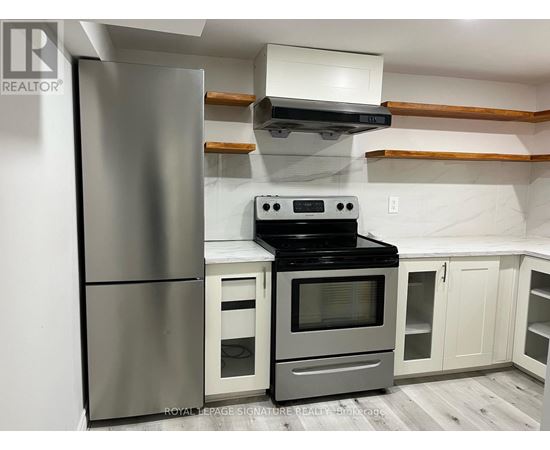 A modern kitchen with a stainless steel refrigerator and an oven with a microwave above it.
