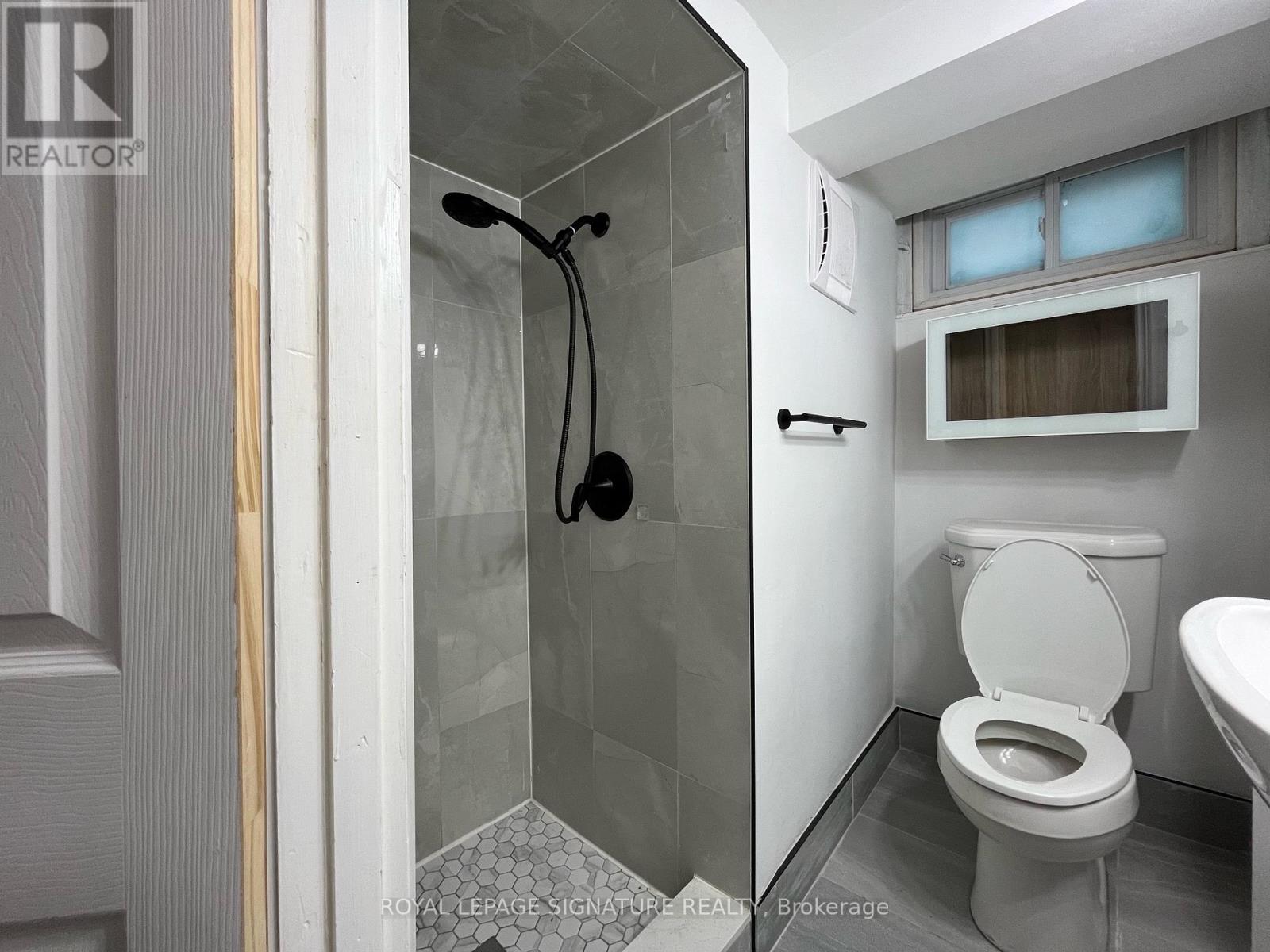 A white toilet in a small bathroom with a glass shower stall.