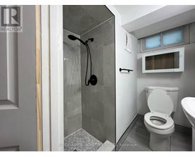 A white toilet in a small bathroom with a glass shower stall.