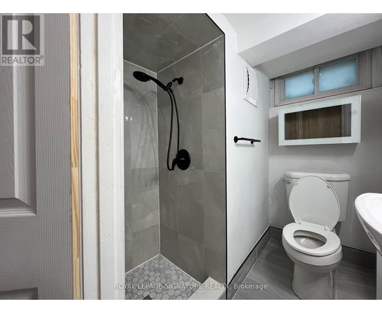 A white toilet in a small bathroom with a glass shower stall.