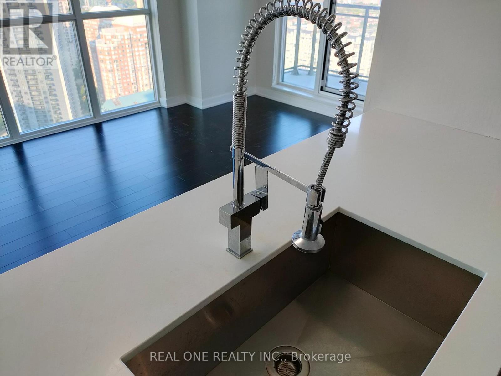A modern kitchen sink with a chrome faucet and a curved hose.