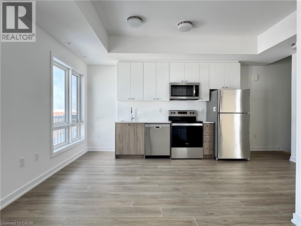 A well-lit kitchen with a refrigerator, oven, and microwave.