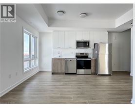 A well-lit kitchen with a refrigerator, oven, and microwave.