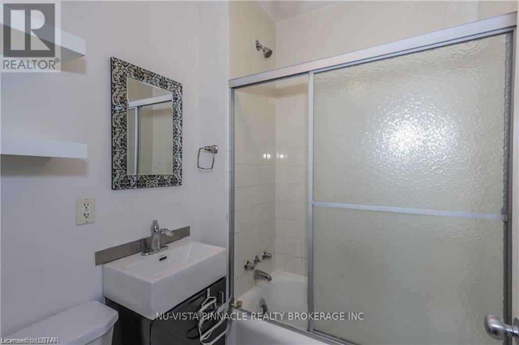 A bathroom with a sink, mirror, and shower.