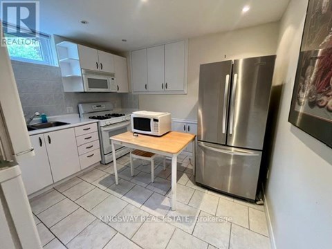 A kitchen with a refrigerator, microwave, and oven.