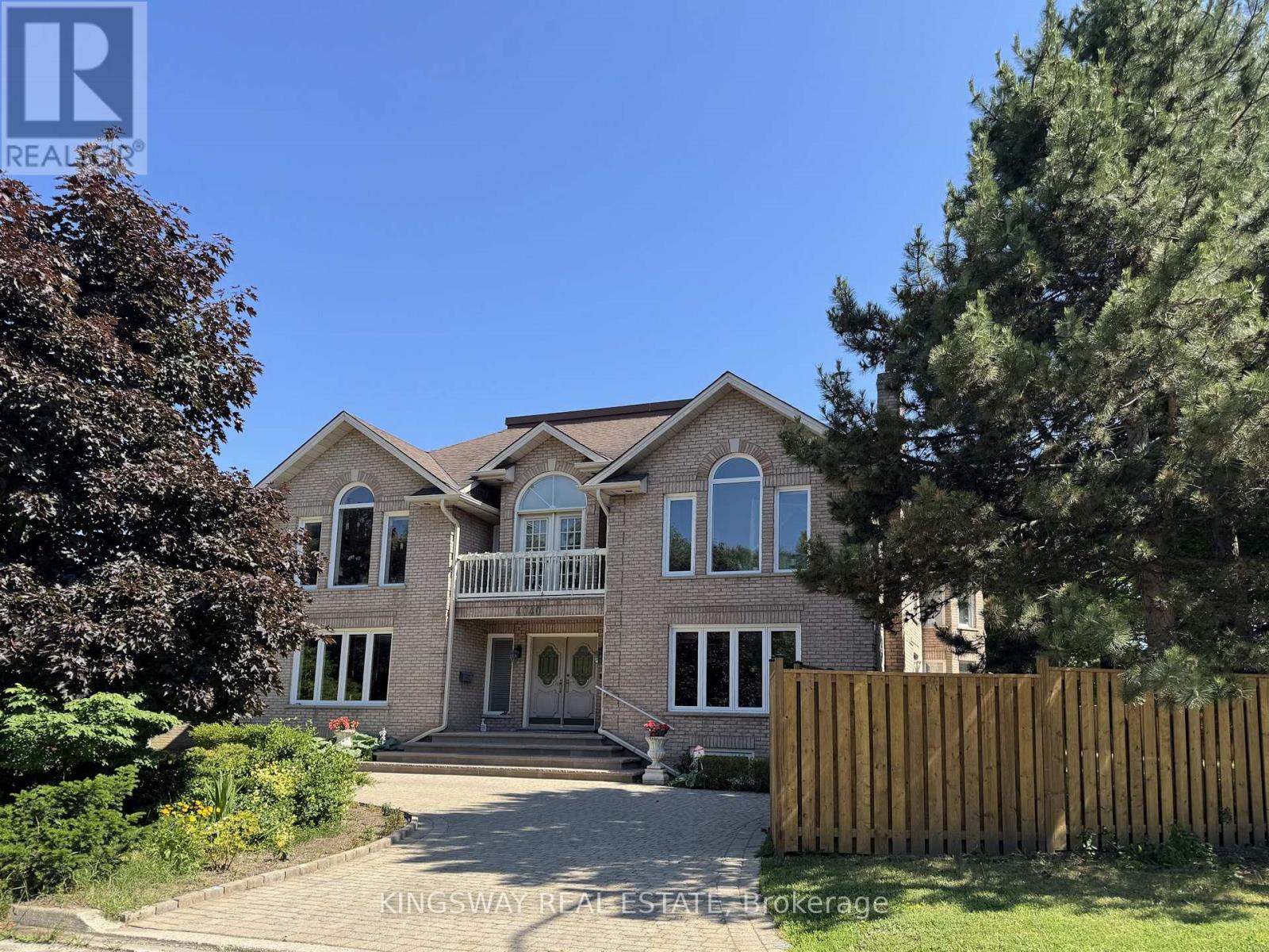 A large house with a driveway and a fence in front of it.