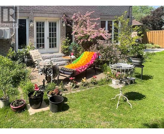 A backyard with a patio, lawn, and a few potted plants.