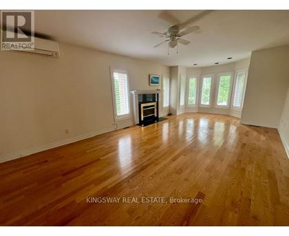 A spacious room with wooden flooring and a ceiling fan.