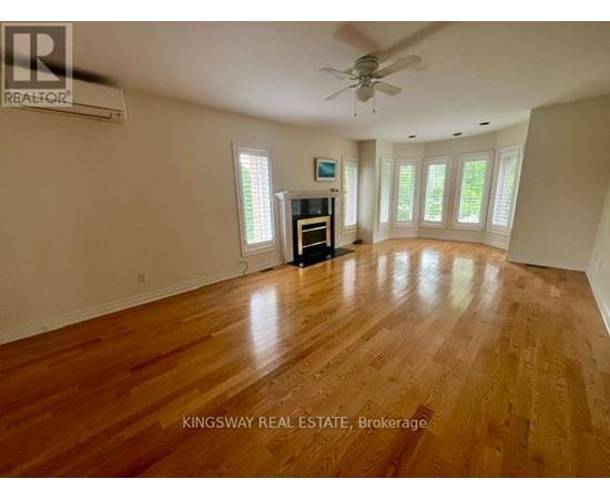 A spacious room with wooden flooring and a ceiling fan.