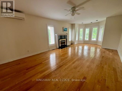 A spacious room with wooden flooring and a ceiling fan.