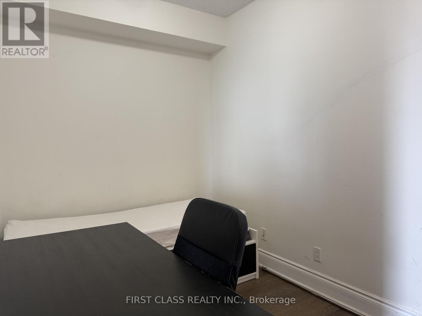 A bedroom with a bed and a chair.