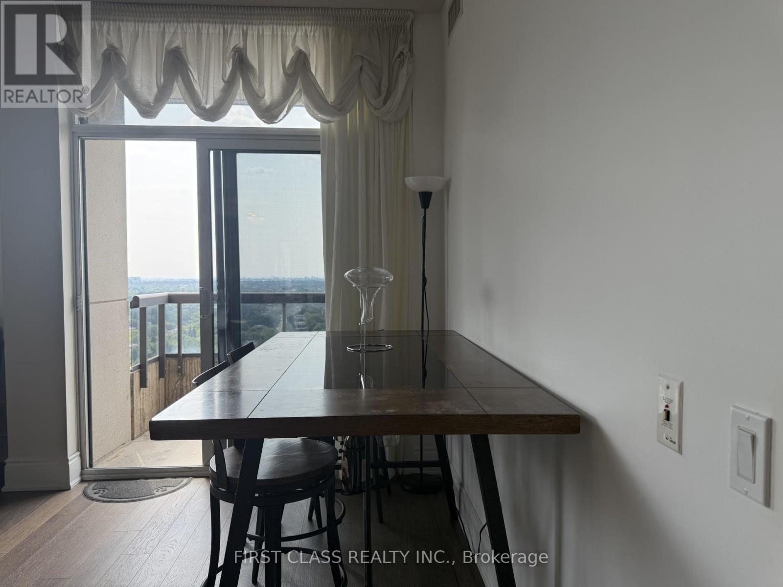 A dining room with a wooden table and chairs with a view of the ocean.