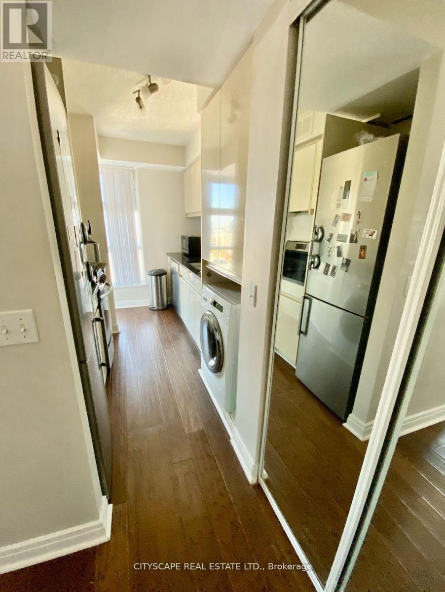 A kitchen with a refrigerator, a washing machine, and a dishwasher.