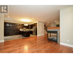 A spacious living room with wood flooring and a fireplace.