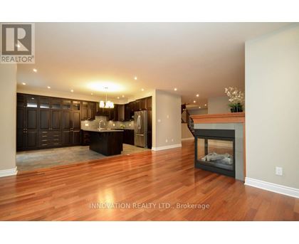 A spacious living room with wood flooring and a fireplace.
