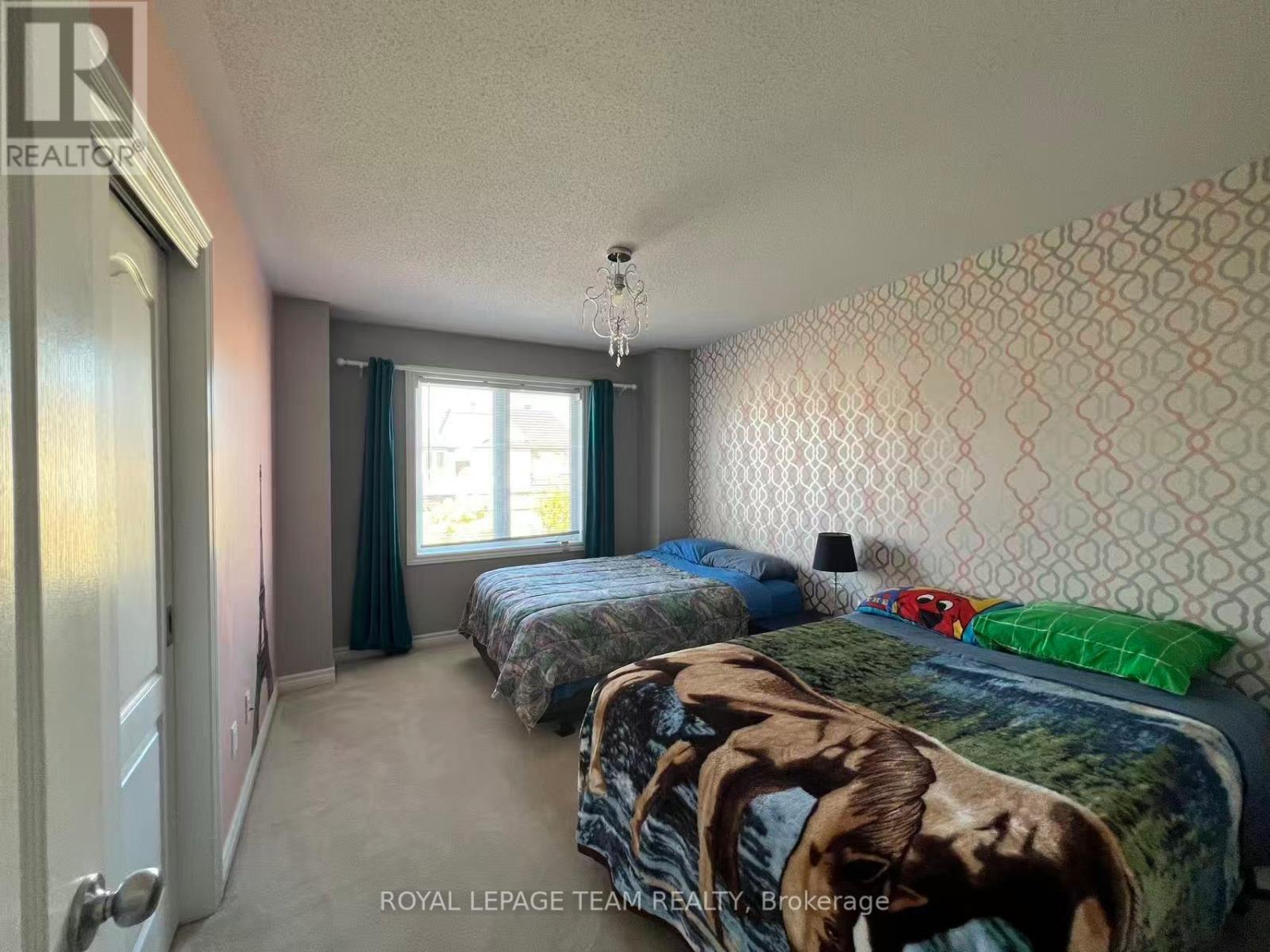 A bedroom with two beds and a chandelier.