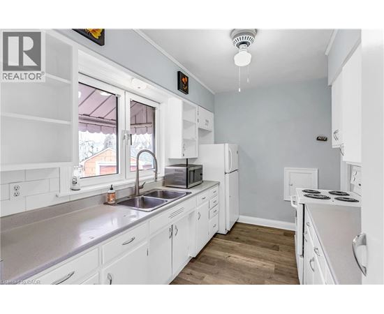 A white kitchen with a sink and a window.