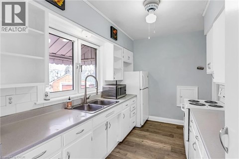 A white kitchen with a sink and a window.