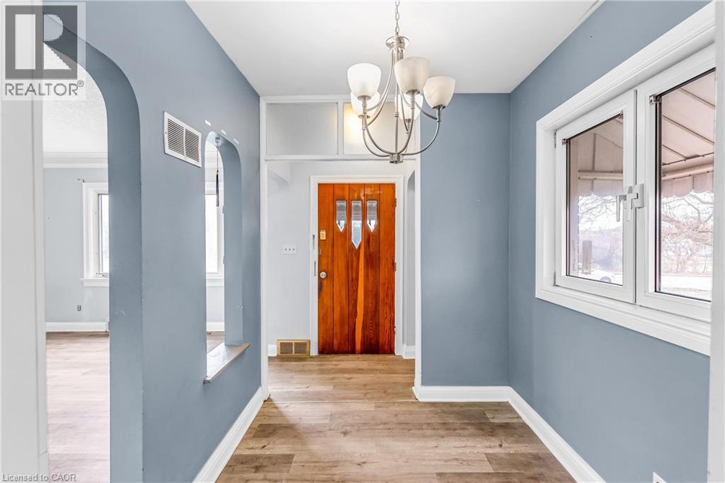 A hallway with a wooden door and a chandelier.