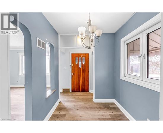 A hallway with a wooden door and a chandelier.