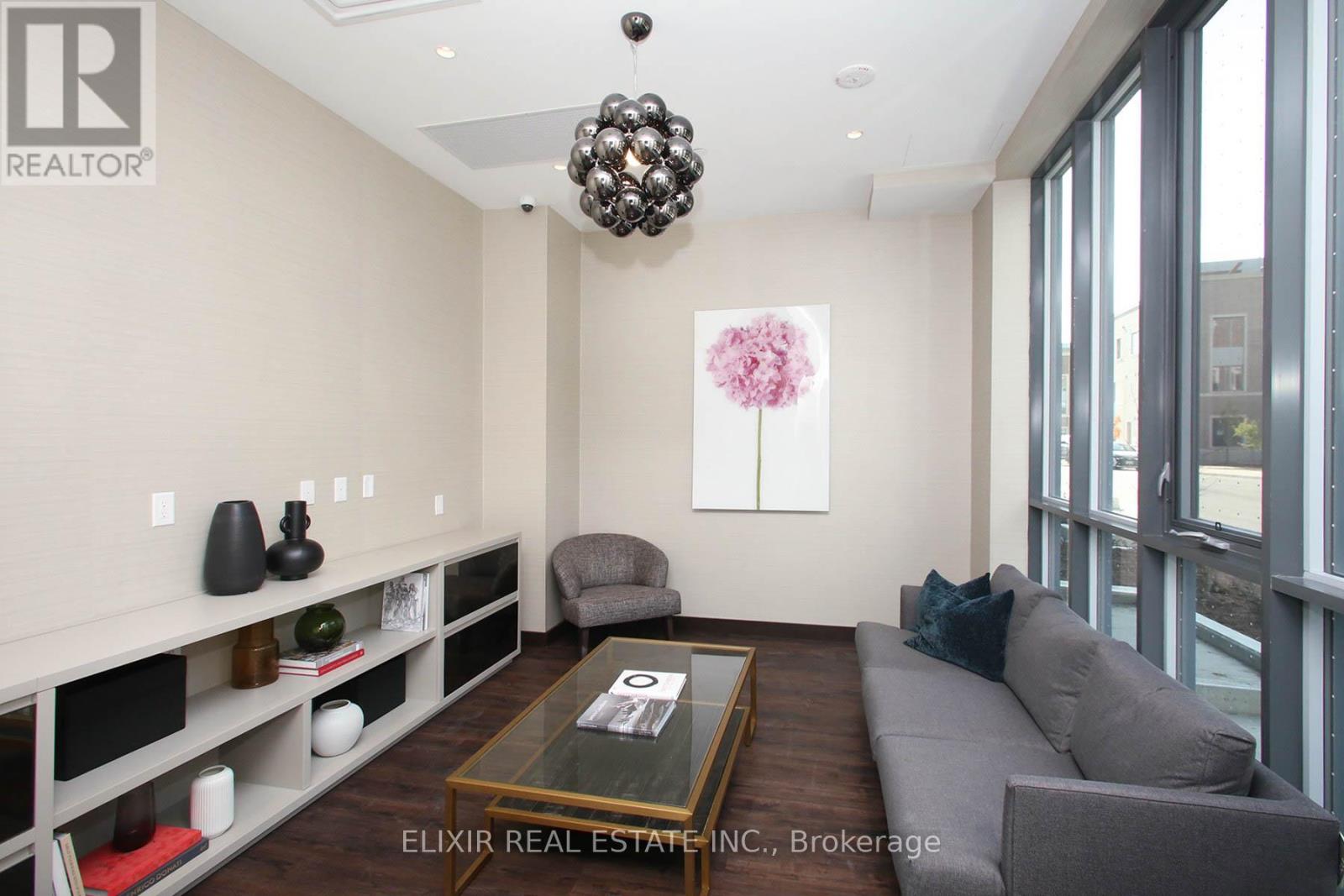 A living room with a grey couch, a coffee table, and a large window.