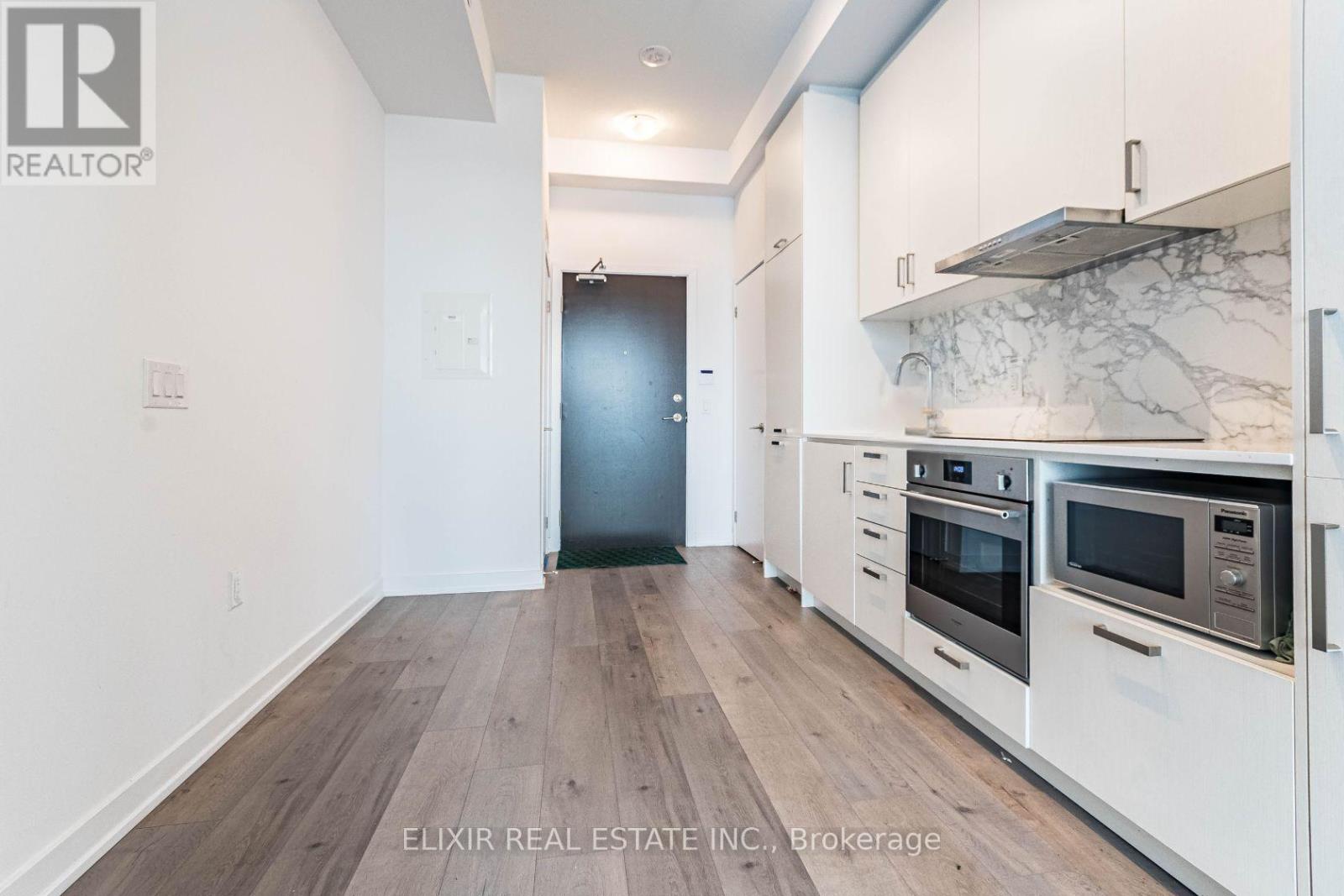 A modern kitchen with white cabinets and a marble backsplash.