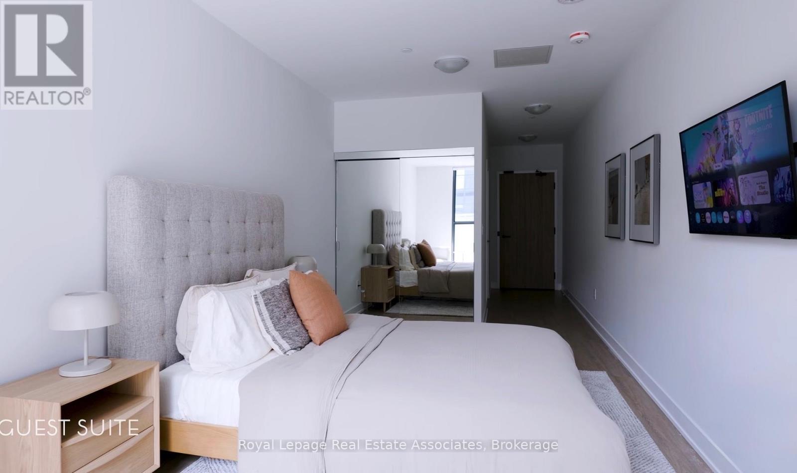 A bedroom with a large bed and a flat screen TV mounted on the wall.