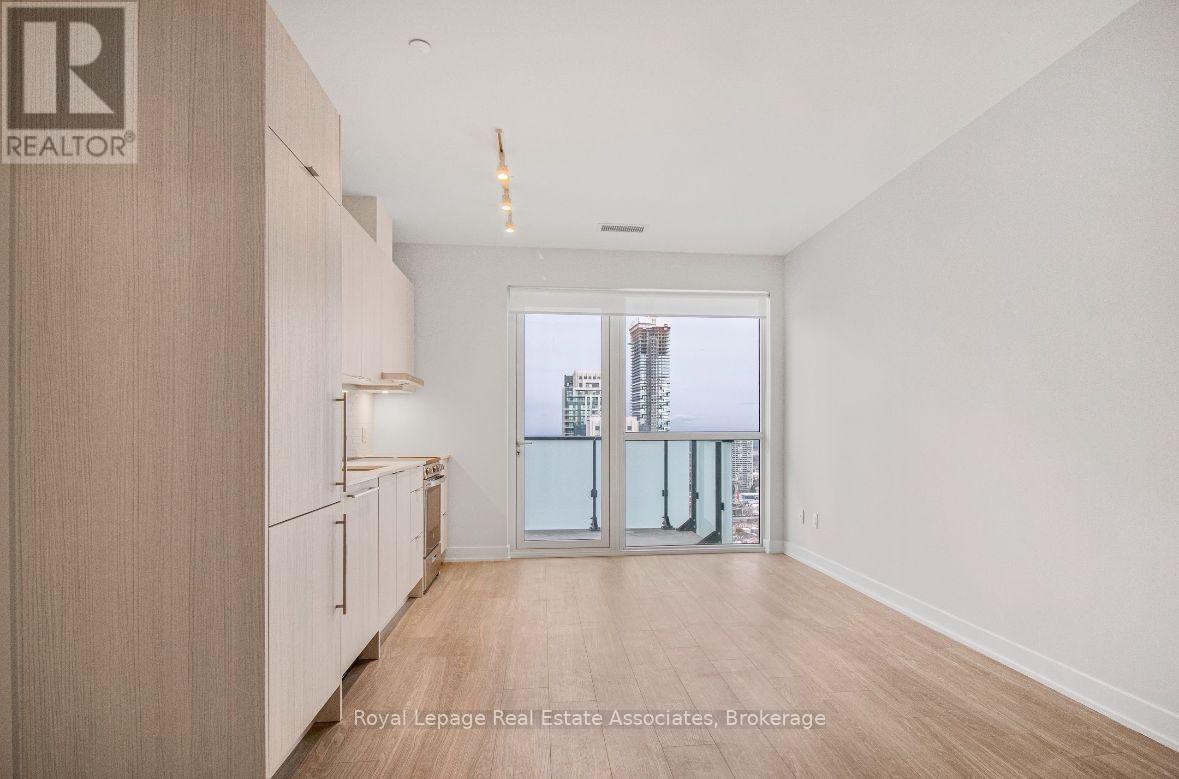 A spacious room with wooden floors and a large window overlooking a cityscape.