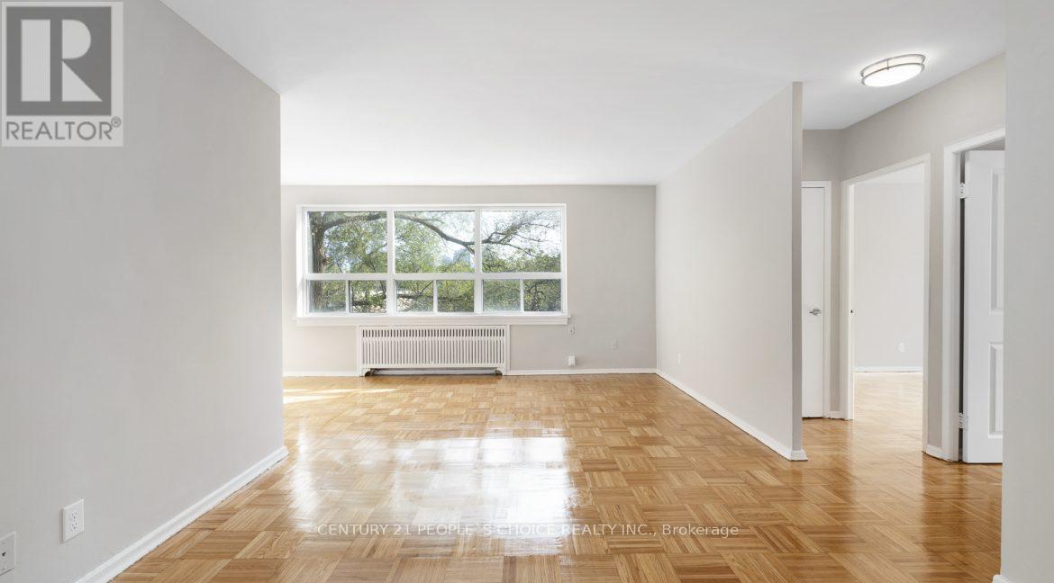 A spacious room with wooden flooring and white walls.