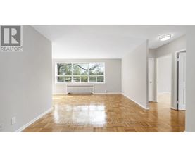 A spacious room with wooden flooring and white walls.