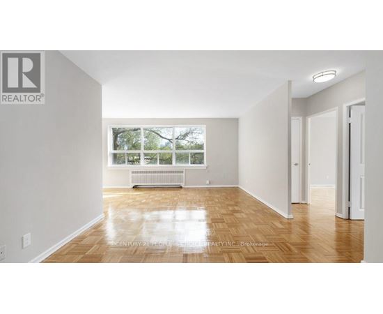 A spacious room with wooden flooring and white walls.