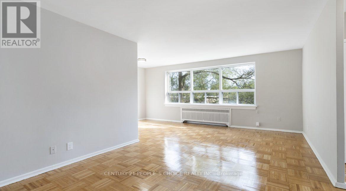 A spacious room with wooden flooring and a large window.