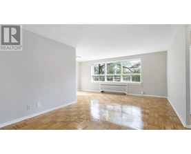 A spacious room with wooden flooring and a large window.