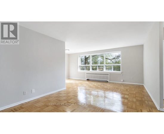 A spacious room with wooden flooring and a large window.