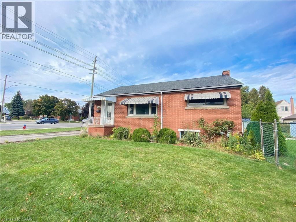 A red brick house with a white window and a fence in front of it.