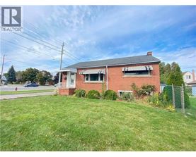 A red brick house with a white window and a fence in front of it.