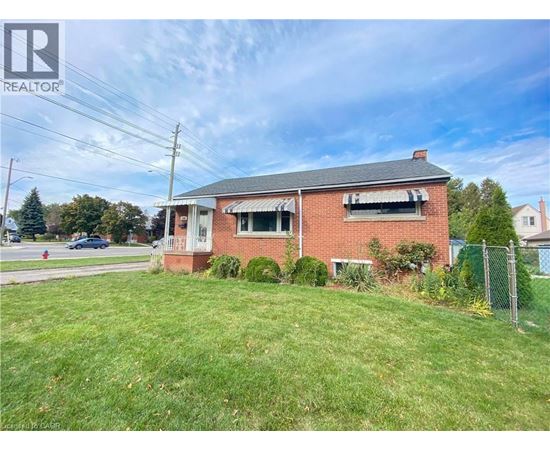 A red brick house with a white window and a fence in front of it.