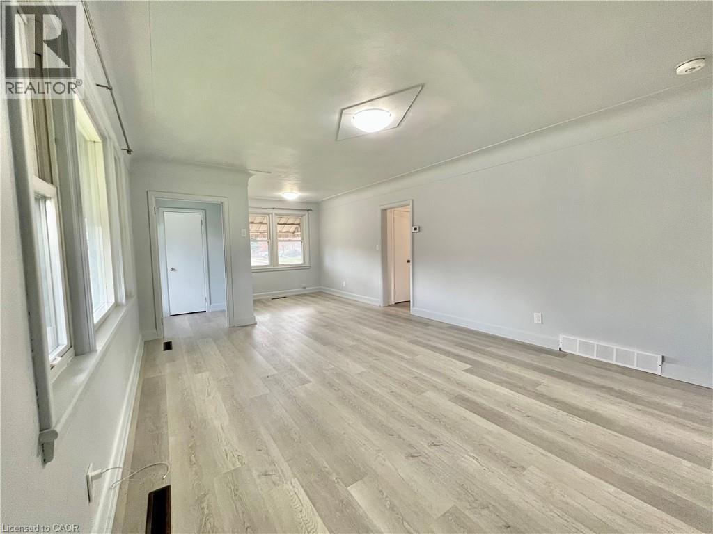 A spacious room with wooden flooring and white walls.