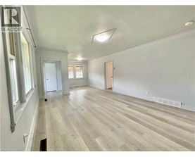 A spacious room with wooden flooring and white walls.