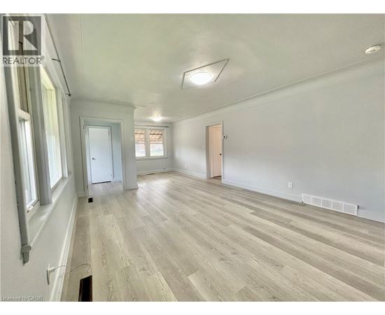 A spacious room with wooden flooring and white walls.