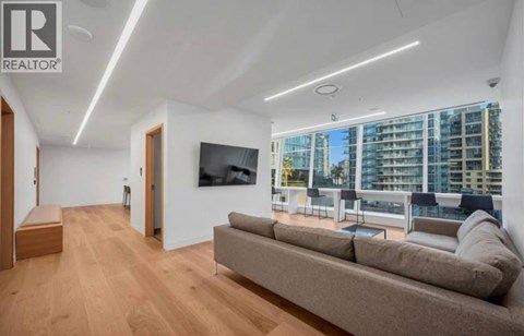 A living room with a large couch and a flat screen TV mounted on the wall.