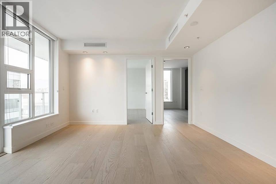 A spacious room with wooden flooring and white walls.