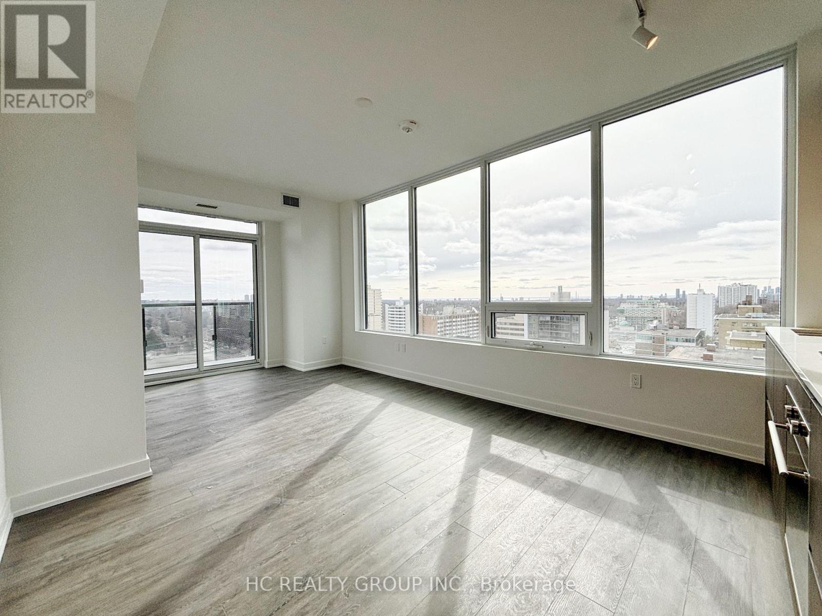 A spacious, empty room with large windows overlooking a cityscape.
