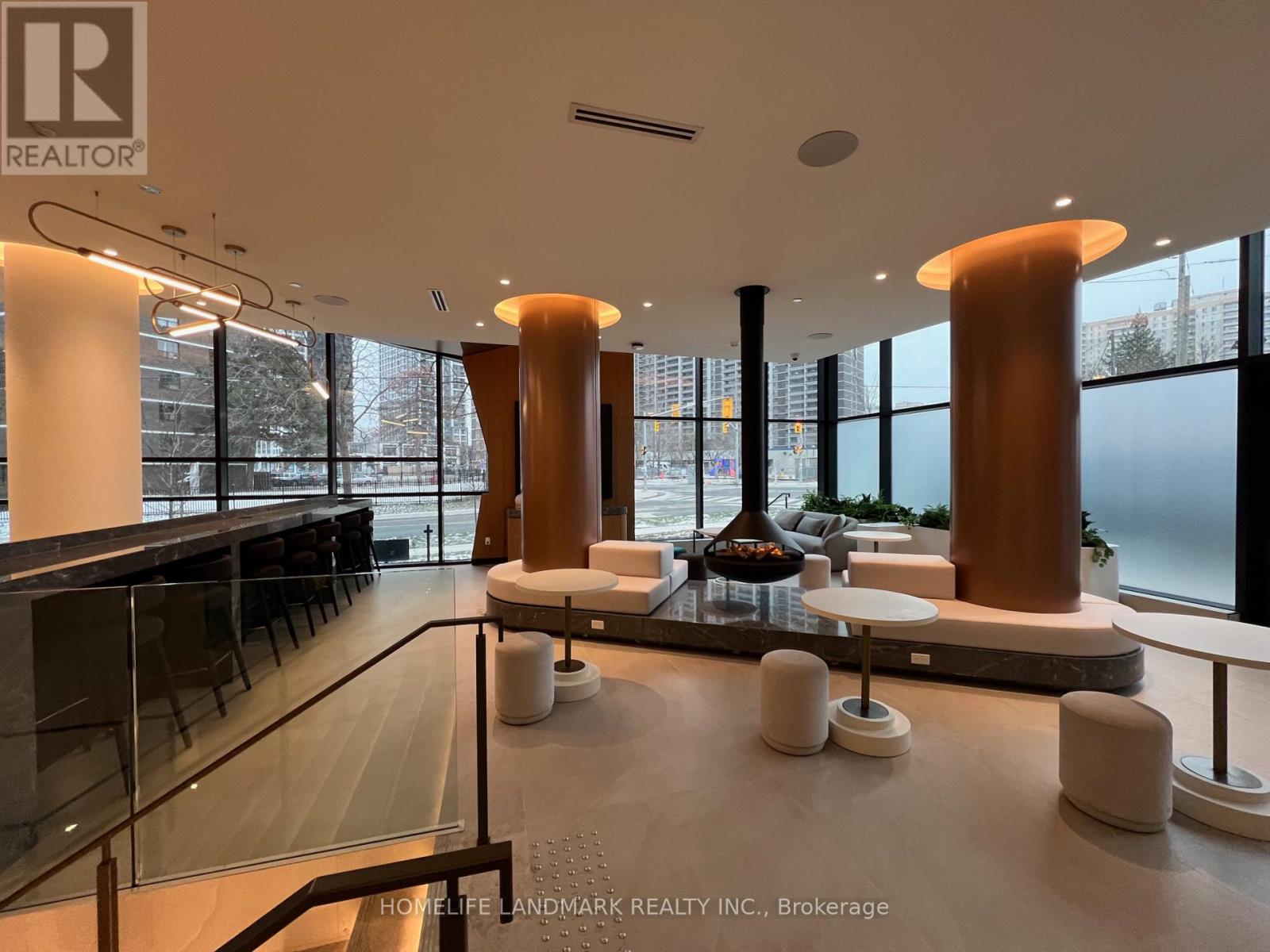 A modern interior space with a glass railing and a long table with white stools.