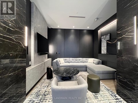 A modern living room with a grey sofa and a black and white rug.